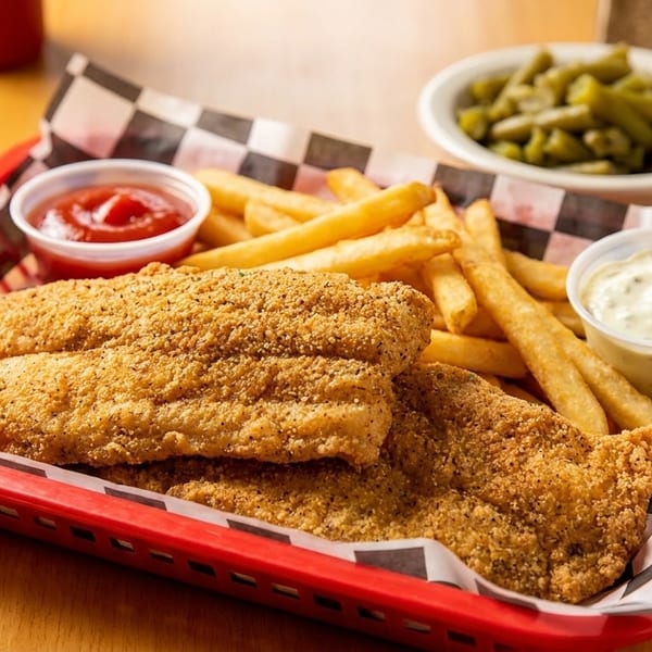Fried fish fillets and french fries in a red basket with ketchup and tartar sauce, and green beans.